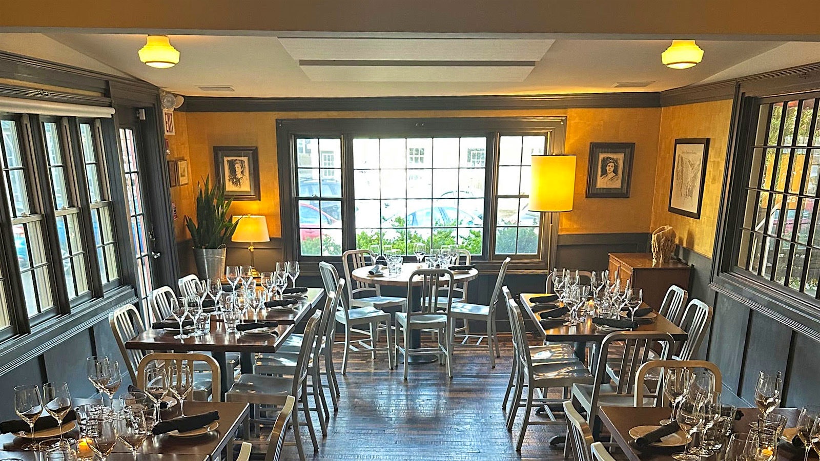 The dining room at Brava, with silver chairs, orange windows and large Federal style windows